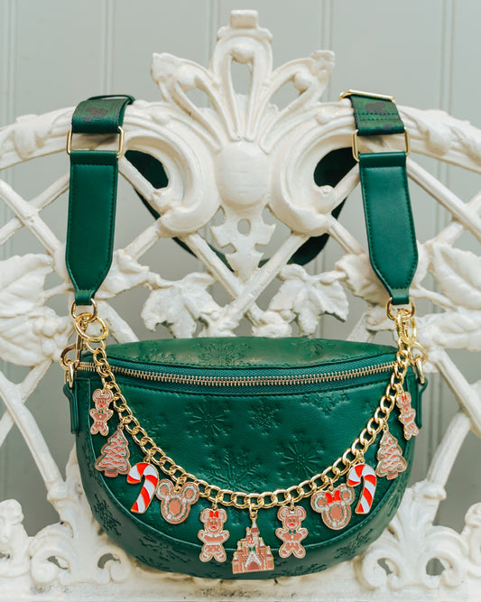 Green handbag with gold chain and festive charms on a decorative chair.